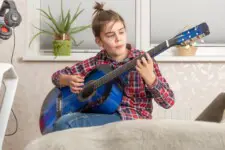 boy teenager playing guitar at home