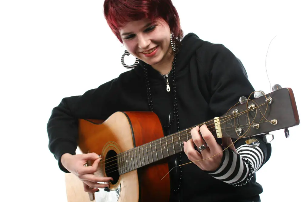 Teenage girl learning to play guitar