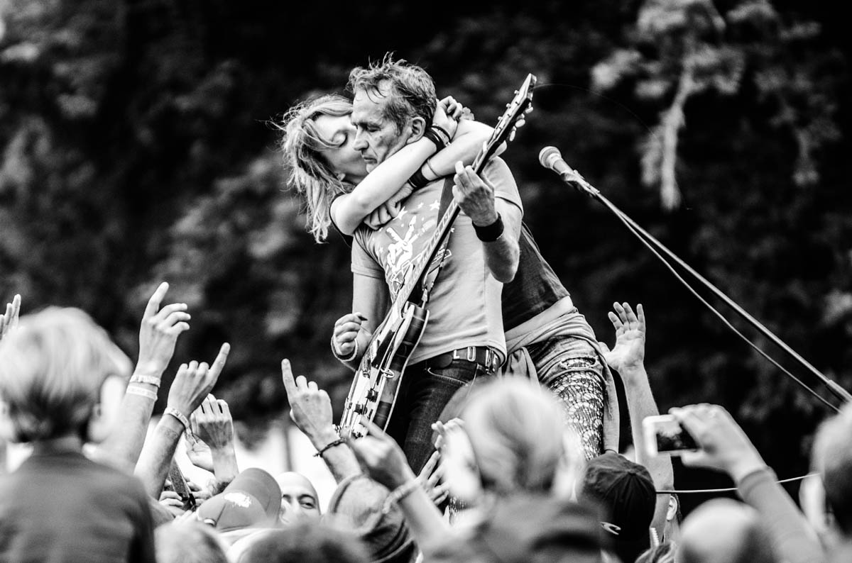 woman kissing guitarist in crowd