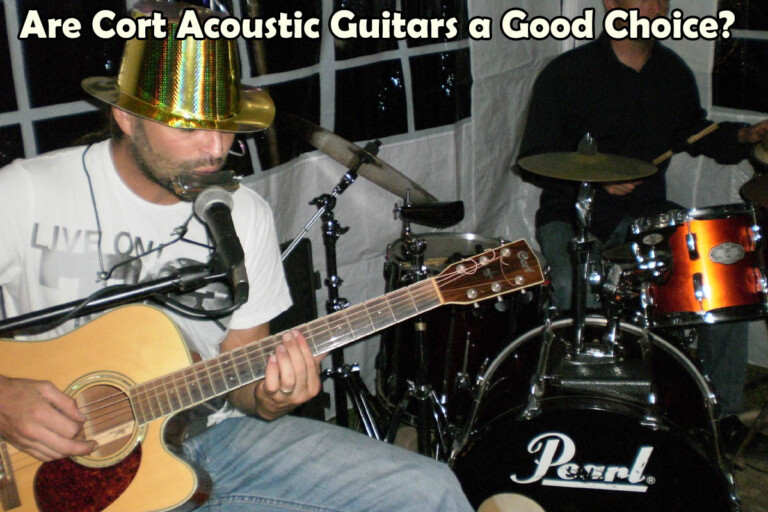 Man wearing party hat playing a cort acoustic guitar with drummer at a party