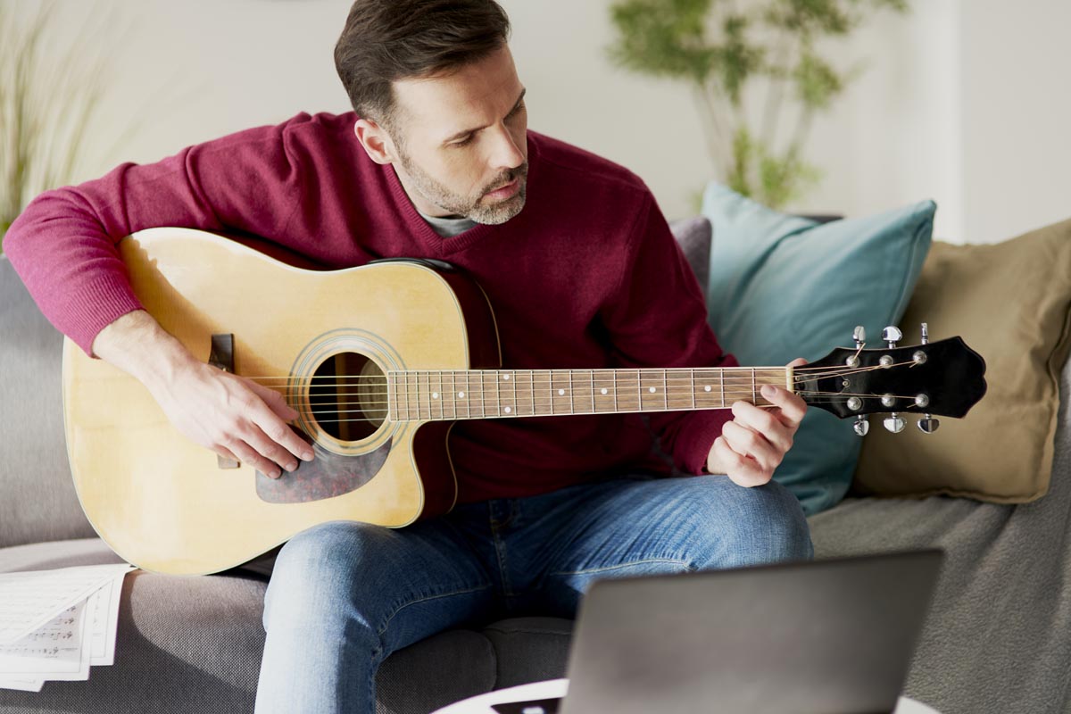 Mid aged man learning guitar online