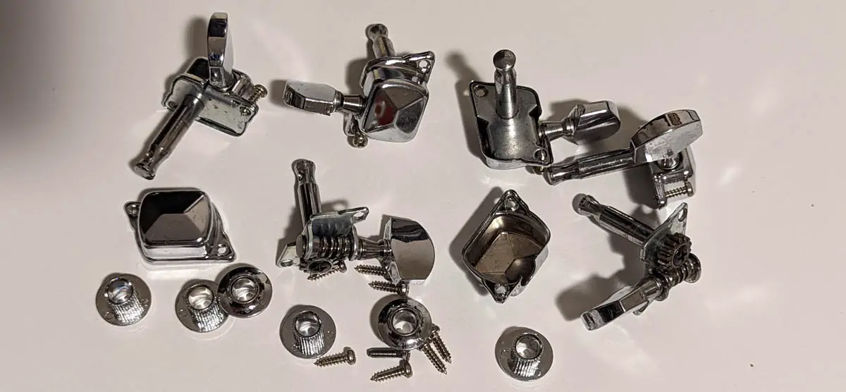 Set of guitar tuning pegs with collars and screws on a white desk
