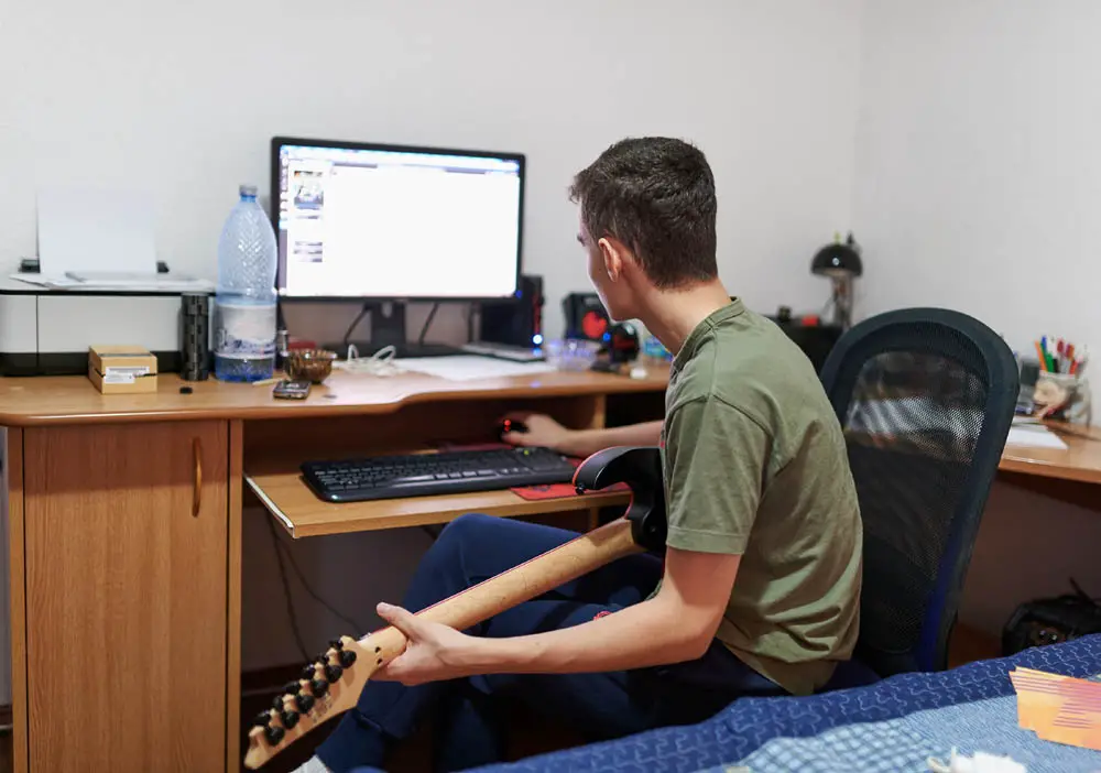 Teenager learning to play electric guitar from online lessons