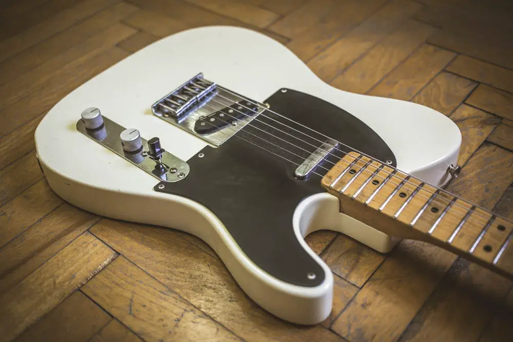 White telecaster electric guitar lying on parquetry floor