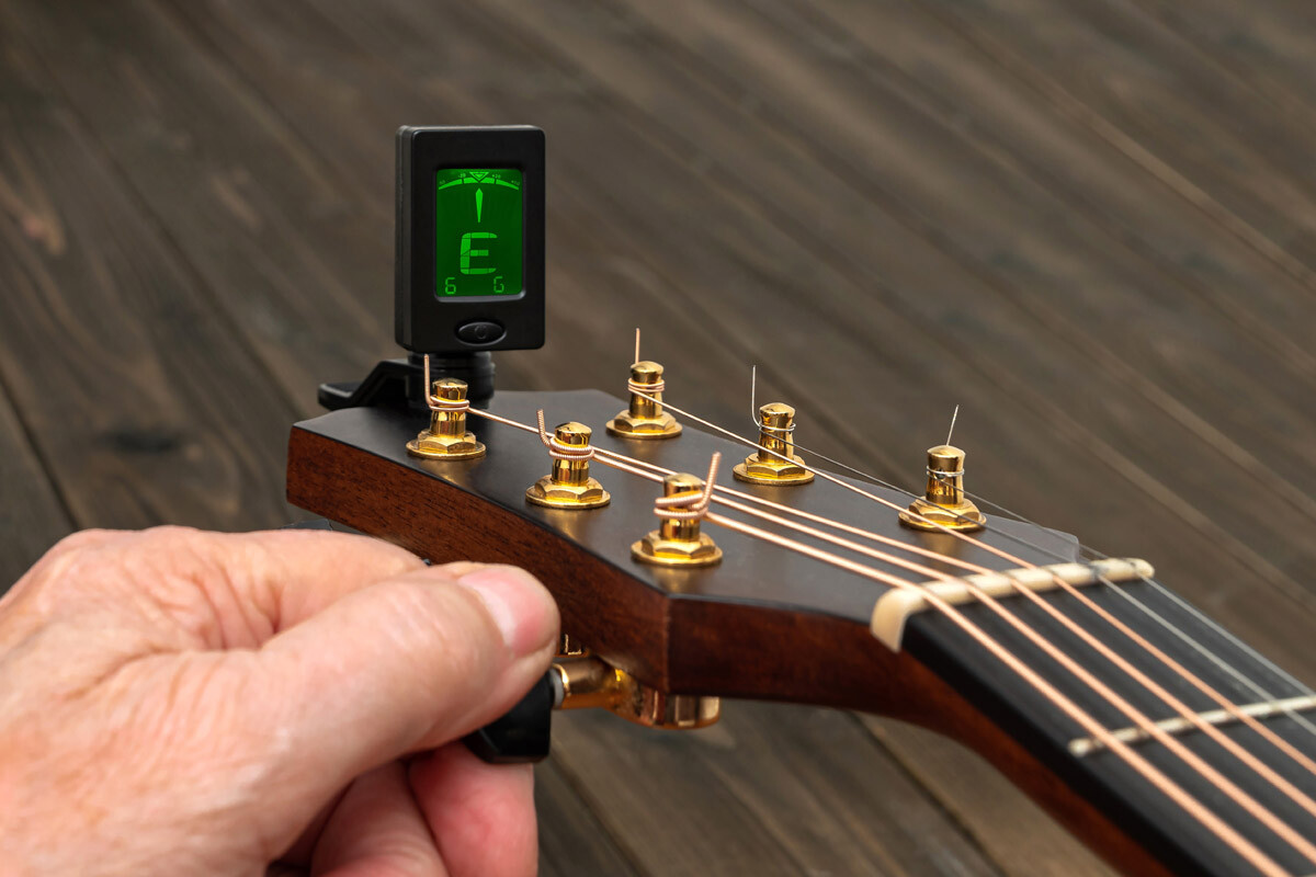Tuning a guitar with a tuner. Close up.